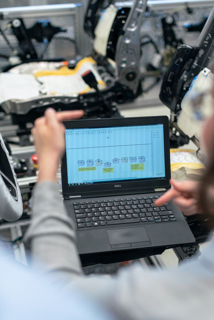 our-experience Engineers using a laptop to analyze software data in an industrial workshop setting.